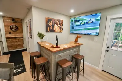 a bar in a home with stools and a tv at Rustic Poconos Ranch w Game Room in Tobyhanna