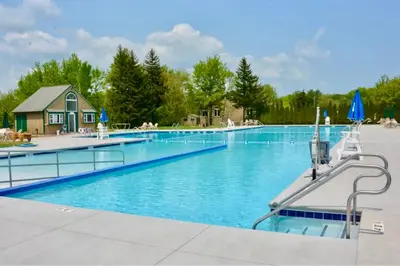 a large swimming pool with a house in the background at Rustic Poconos Ranch w Game Room in Tobyhanna