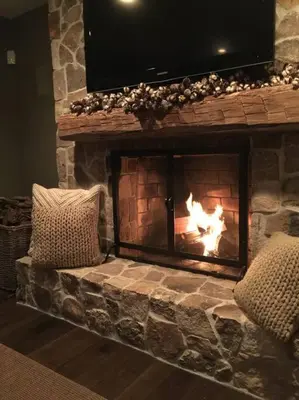 a stone fireplace with two pillows in front of it at private luxe, garden, wellness home steps from Princeton in Franklin Park