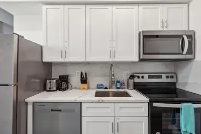 a kitchen with white cabinets and a sink and a microwave at Stay at Luna at Convention Center in Philadelphia