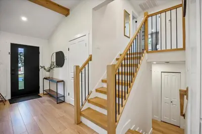 a staircase in a home with white walls and wood floors at Modern Mid-Century Retreat in West Chester
