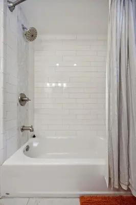 a white bath tub with a shower curtain in a bathroom at Modern Mid-Century Retreat in West Chester