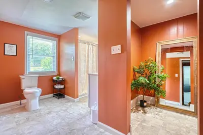 a bathroom with orange walls and a toilet and a tree at The Farm House in Dillsburg