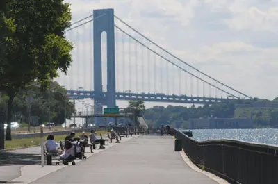 people sitting on benches in front of a bridge at Bay Ridge ApartHotel in Brooklyn