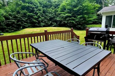 a picnic table and chairs on a deck with a grill at Perfect Vacation Home with Game Room Theater Hot Tub in Tobyhanna
