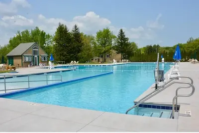 a large swimming pool with a house in the background at Perfect Vacation Home with Game Room Theater Hot Tub in Tobyhanna