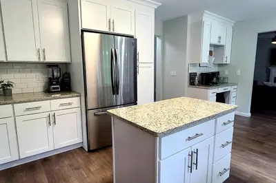 a kitchen with white cabinets and a stainless steel refrigerator at Perfect Vacation Home with Game Room Theater Hot Tub in Tobyhanna