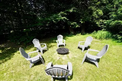 a group of chairs and a table in the grass at Perfect Vacation Home with Game Room Theater Hot Tub in Tobyhanna