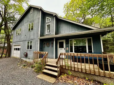 a blue house with a porch and a fence at Poconos Oasis with Game Room in Pocono Summit