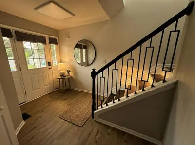 a hallway with a staircase with a mirror and a door at Cozy Modern Villa in New Castle