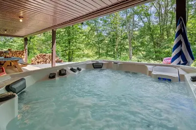 a large hot tub in a backyard with at WaterFront Cabin Hot Tub Kayaks Firepit Game Consoles in Tunkhannock