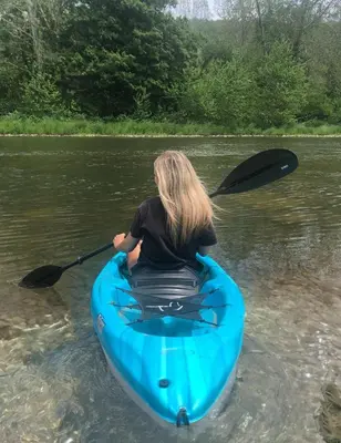 a woman in a blue kayak in the water at WaterFront Cabin Hot Tub Kayaks Firepit Game Consoles in Tunkhannock
