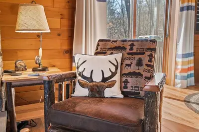 a chair with a pillow on it next to a desk at WaterFront Cabin Hot Tub Kayaks Firepit Game Consoles in Tunkhannock
