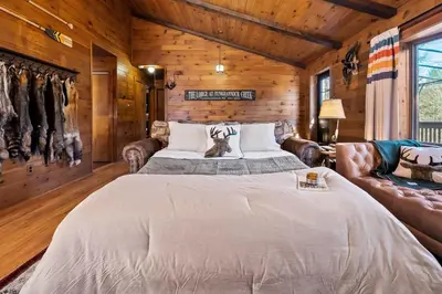 a bedroom with a large bed and leather furniture at WaterFront Cabin Hot Tub Kayaks Firepit Game Consoles in Tunkhannock