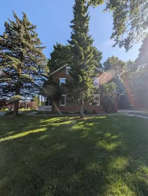 a house with two trees in front of a yard at The Hidden Homestead in Lebanon