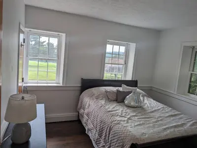 a bedroom with a bed and two windows at The Hidden Homestead in Lebanon