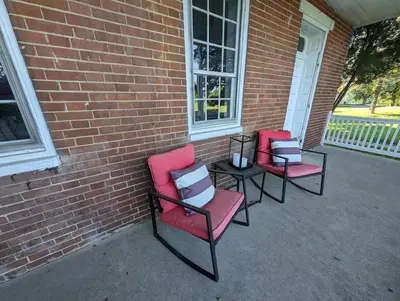 three chairs sitting next to a brick building at The Hidden Homestead in Lebanon