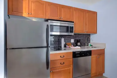 a kitchen with a stainless steel refrigerator and wooden cabinets at Hyatt House Philadelphia/Plymouth Meeting in East Norriton