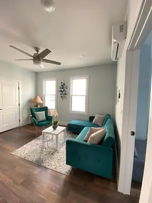 a living room with a green couch and a table at MetLife Stadium Apartments Near NYC in Jersey City