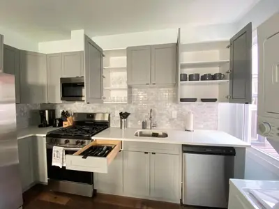 a kitchen with white cabinets and a stove top oven at MetLife Stadium Apartments Near NYC in Jersey City
