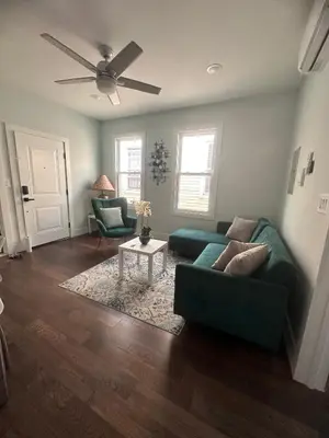 a living room with a green couch and a ceiling fan at MetLife Stadium Apartments Near NYC in Jersey City