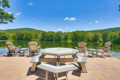 a patio with tables and chairs and a lake at Delaware River Access Peaceful Farm Retreat! in Callicoon