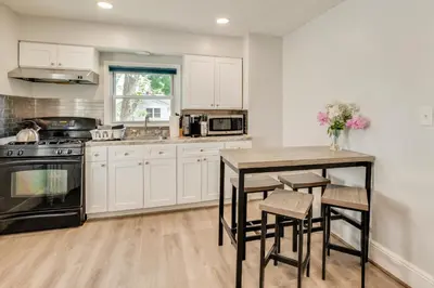 a kitchen with white cabinets and a table and chairs at Hackensack Escape with Yard - 17 Mi to Times Square! in Hackensack