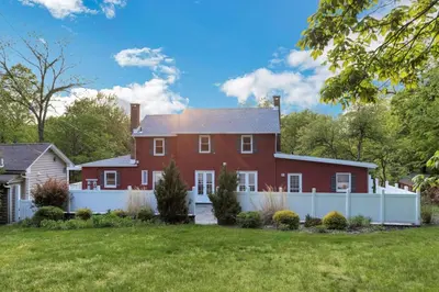 a large red house with a white fence at Enchanting Historic Home near West Point Beacon in Cornwall-on-Hudson