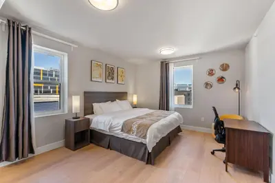 a bedroom with a bed and a desk and windows at 4211 Suites in Philadelphia