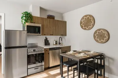 a kitchen with a stainless steel refrigerator and a table with chairs at 4211 Suites in Philadelphia