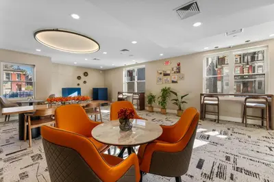 a waiting room with orange chairs and a table at 4211 Suites in Philadelphia