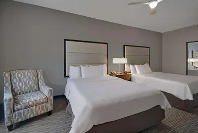 a hotel room with two beds and a chair at Homewood Suites by Hilton Hamilton, NJ in Hamilton