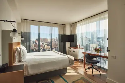 a bedroom with a bed and a desk and a large window at Hotel Indigo Lower East Side New York by IHG in New York