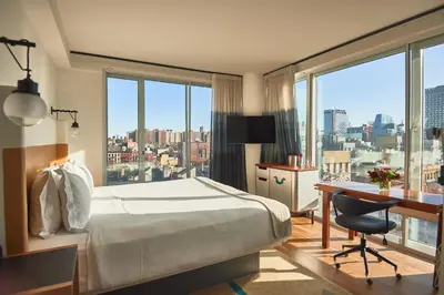 a hotel room with a bed and a desk and windows at Hotel Indigo Lower East Side New York by IHG in New York