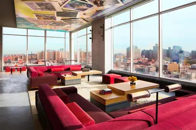 a living room with red furniture and large windows at Hotel Indigo Lower East Side New York by IHG in New York