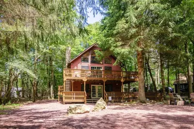 a log cabin in the woods with a tree at Hot Tub l Walk to Lake Harmony l Minutes to Ski in Lake Harmony