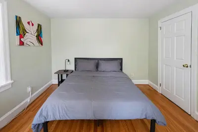 a bed in a white bedroom with a wooden floor at Stylish & Charming 2BR Monthly Discount in Elkins Park