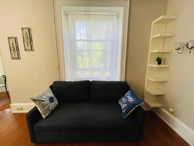 a black couch in a living room with a window at Stylish & Charming 2BR Monthly Discount in Elkins Park