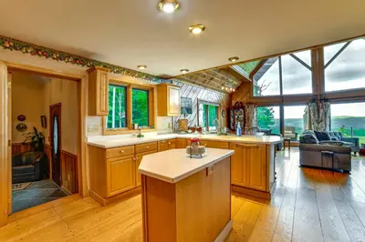 a large kitchen with wooden cabinets and a living room at Secluded Oxford Cabin on 75 Acres Sunset Views! in Oxford