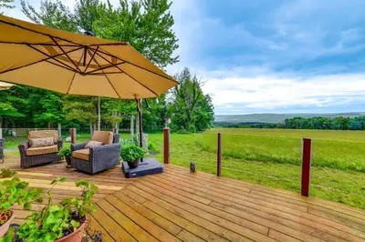 a wooden deck with an umbrella and chairs on it at Secluded Oxford Cabin on 75 Acres Sunset Views! in Oxford