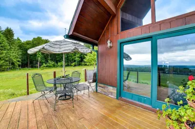 a patio with a table and chairs and an umbrella at Secluded Oxford Cabin on 75 Acres Sunset Views! in Oxford