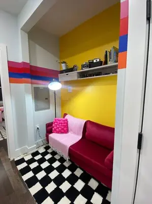 a living room with a red couch and a colorful wall at Heart of NY - 17 min to Empire State & Times Sq in Jersey City