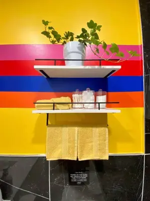 a colorful wall with a shelf with towels and a plant at Heart of NY - 17 min to Empire State & Times Sq in Jersey City