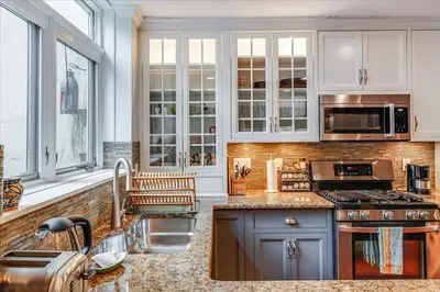 a kitchen with white cabinets and a sink at Artist Residence 3 Bedroom Brownstone in Hoboken