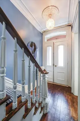 a hallway with stairs with a chandelier and a door at Artist Residence 3 Bedroom Brownstone in Hoboken