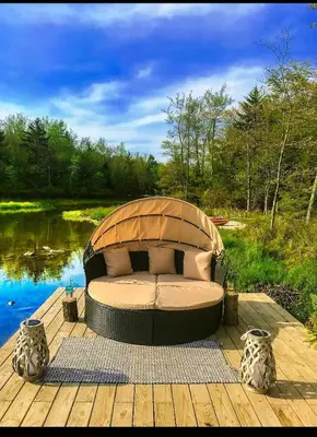 a bed sitting on a dock next to a body of water at Majestic Lake Front Chalet in Tobyhanna