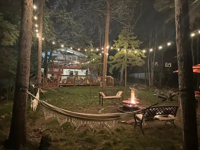 a hammock in a park at night with a fire at Majestic Lake Front Chalet in Tobyhanna