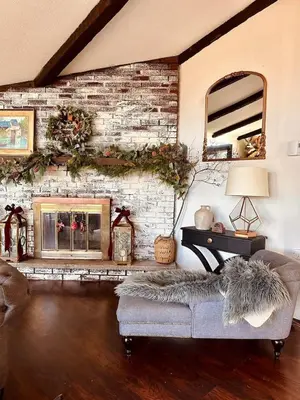 a living room with a brick wall with a fireplace at Majestic Lake Front Chalet in Tobyhanna