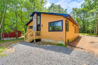 a tiny house in the woods with a porch at Private Hot Tub Charming Poconos Cabin! in Albrightsville