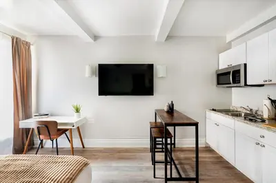 a white kitchen with a small table and a kitchen at 73-410 Luxury 24 DM New Studio UWS Gym Laundry in New York